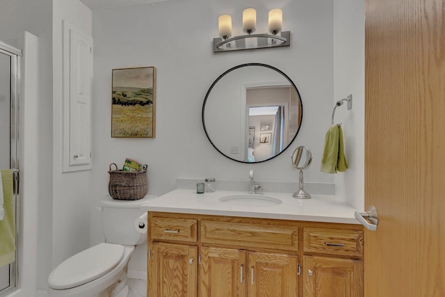 bathroom featuring vanity, a shower with door, and toilet