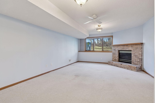 unfurnished living room featuring ceiling fan, a brick fireplace, carpet floors, and a textured ceiling