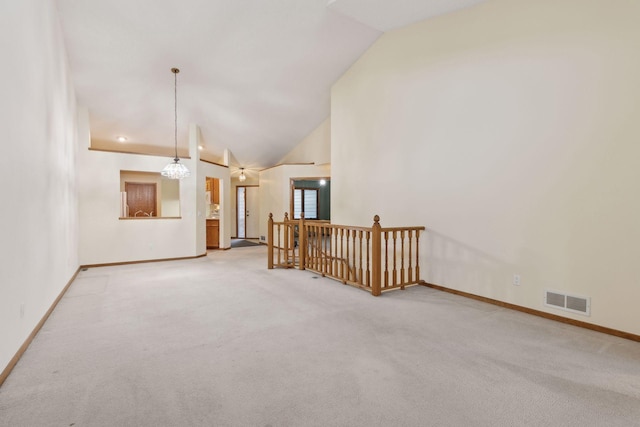 unfurnished living room with lofted ceiling, a chandelier, and carpet