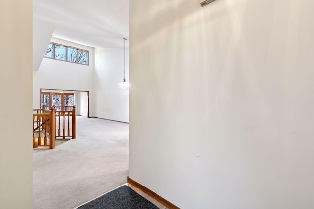 hall featuring a towering ceiling and carpet flooring