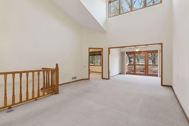 spare room with a high ceiling, ceiling fan, and light carpet