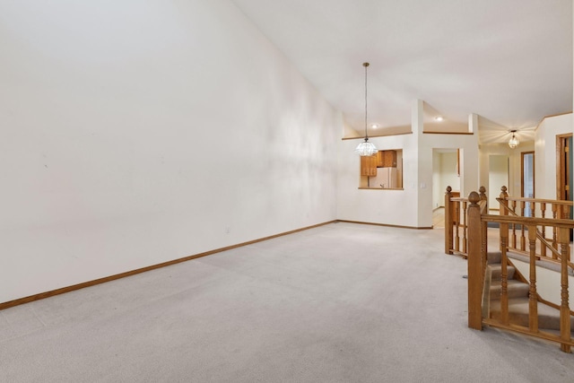 spare room featuring lofted ceiling, a notable chandelier, and light colored carpet