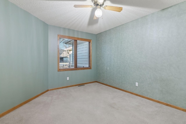 carpeted spare room featuring a textured ceiling and ceiling fan