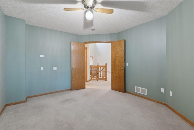 spare room with a textured ceiling, ceiling fan, and light colored carpet