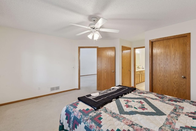 carpeted bedroom with ensuite bath, a textured ceiling, and ceiling fan