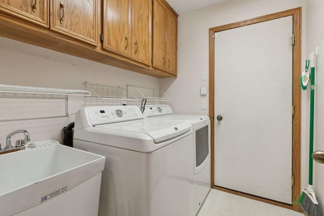 laundry room with sink, washing machine and clothes dryer, and cabinets