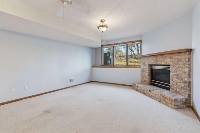 unfurnished living room featuring a textured ceiling, a fireplace, ceiling fan, and carpet