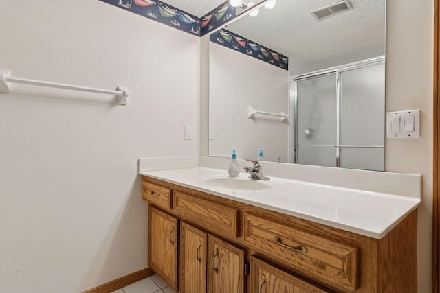 bathroom featuring a textured ceiling, walk in shower, tile patterned flooring, and vanity