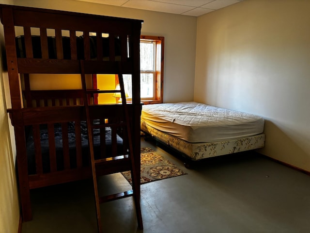 bedroom with a drop ceiling and concrete floors