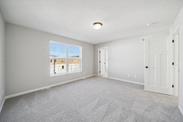 spare room with light colored carpet and a textured ceiling