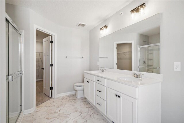 bathroom featuring vanity, toilet, and a shower with door