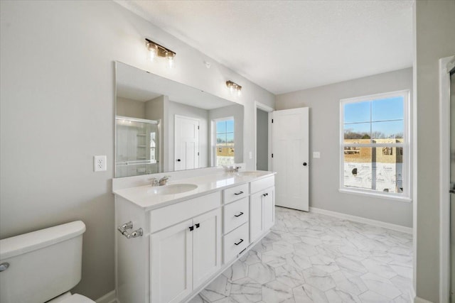 bathroom with vanity, toilet, a shower with shower door, and a wealth of natural light