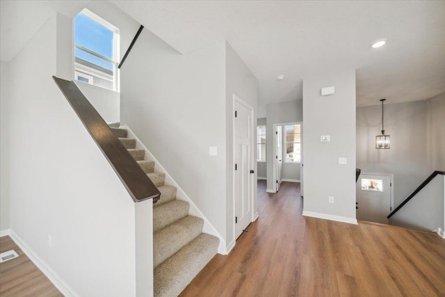 staircase featuring hardwood / wood-style floors and an inviting chandelier