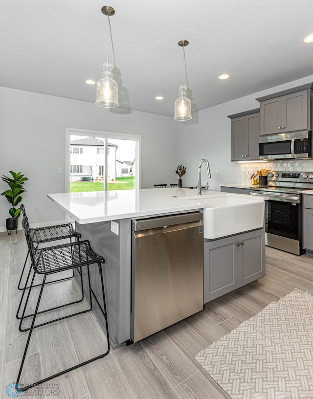 kitchen with stainless steel appliances, gray cabinets, a sink, and recessed lighting
