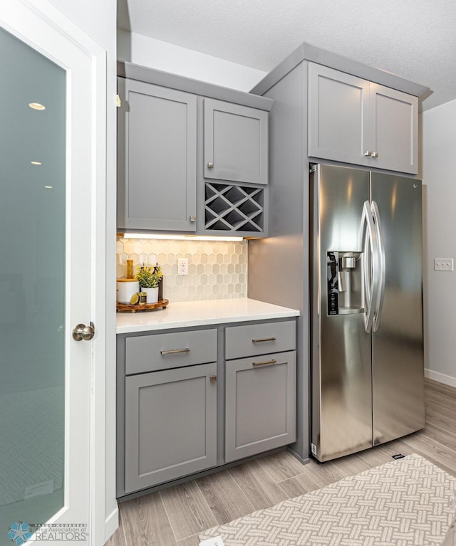 kitchen featuring gray cabinets, light wood-type flooring, and stainless steel fridge