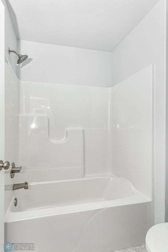 bathroom with toilet and bathing tub / shower combination