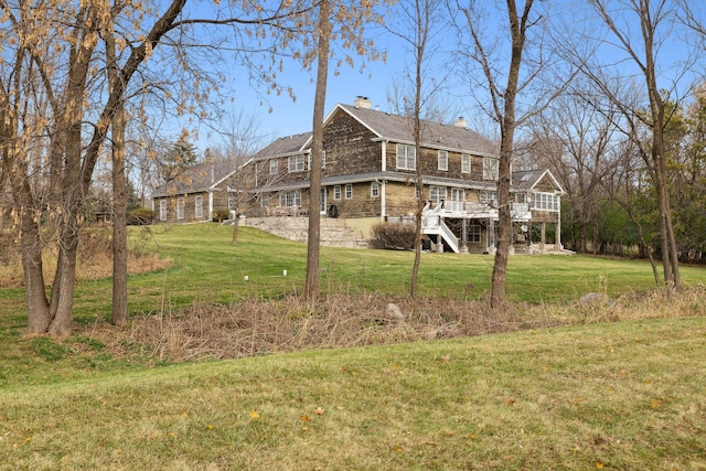 view of side of property with a chimney, a lawn, stairway, and a wooden deck