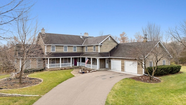 view of front of house featuring a chimney, aphalt driveway, an attached garage, a porch, and a front yard