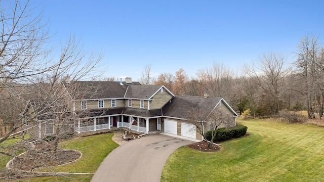 view of front of home featuring an attached garage, aphalt driveway, a chimney, and a front lawn