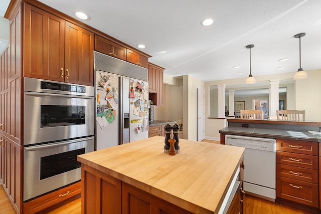 kitchen with decorative columns, dishwasher, a center island, double oven, and wooden counters