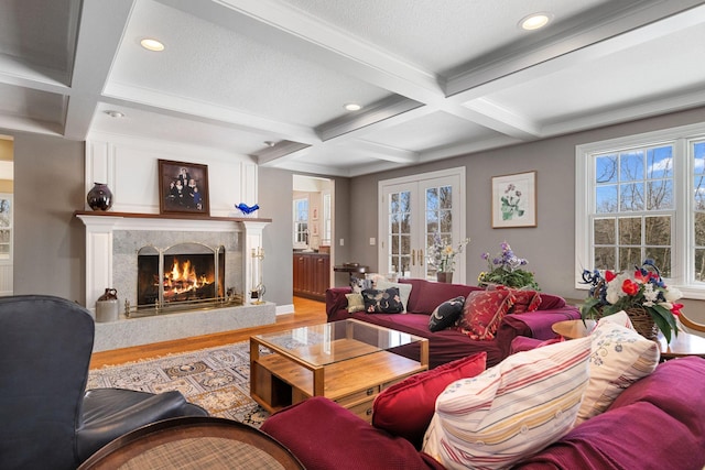 living area featuring french doors, beam ceiling, a fireplace, wood finished floors, and coffered ceiling