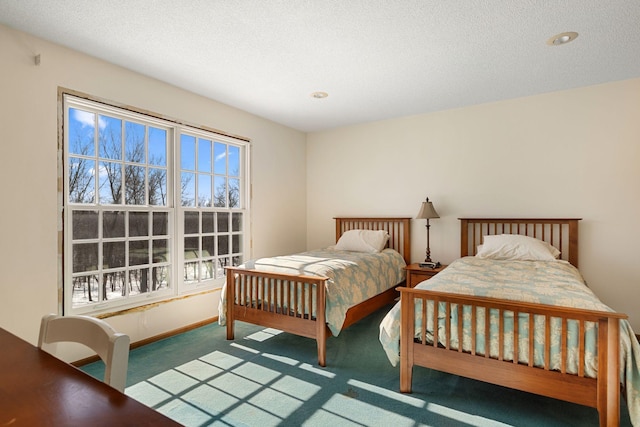 bedroom with a textured ceiling, dark carpet, and baseboards