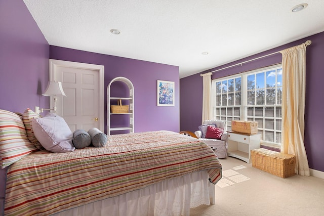 bedroom with baseboards, a textured ceiling, and light colored carpet