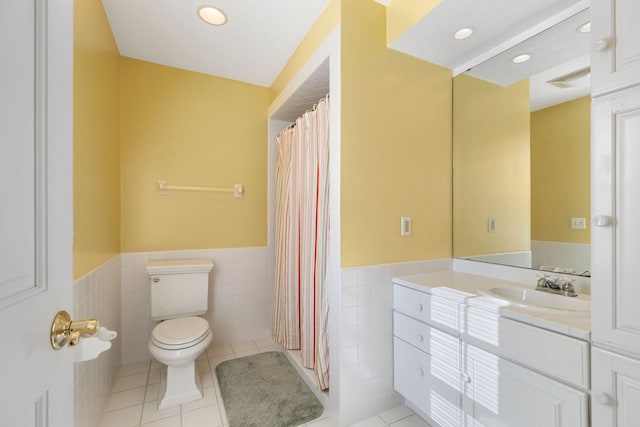 bathroom with toilet, vanity, tile walls, and tile patterned floors