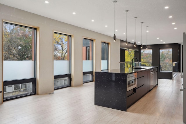 kitchen with a spacious island, sink, hanging light fixtures, and plenty of natural light