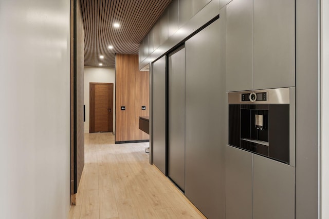 corridor with light hardwood / wood-style flooring and wooden ceiling