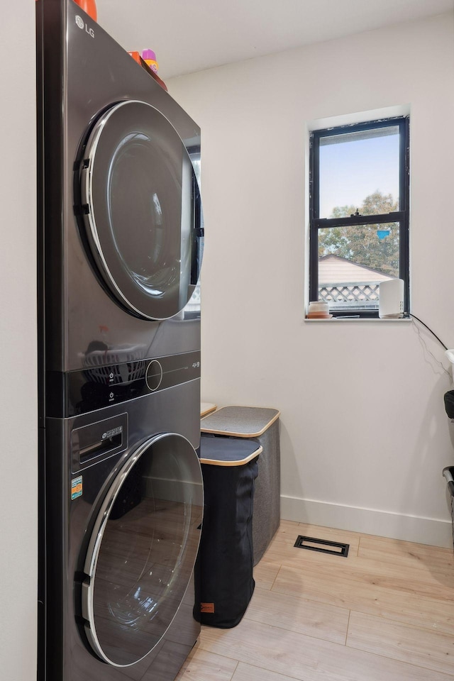 washroom with stacked washer / dryer and light wood-type flooring