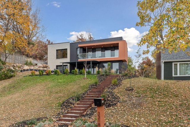 rear view of property with a lawn and a balcony