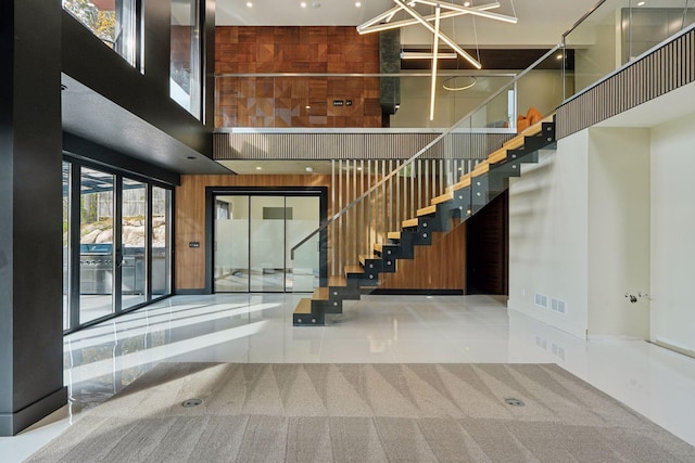 stairs with wood walls, a towering ceiling, and tile patterned flooring