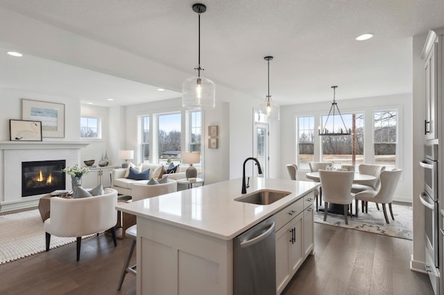 kitchen featuring an island with sink, white cabinetry, a wealth of natural light, pendant lighting, and sink