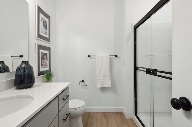 bathroom with vanity, toilet, an enclosed shower, and hardwood / wood-style floors