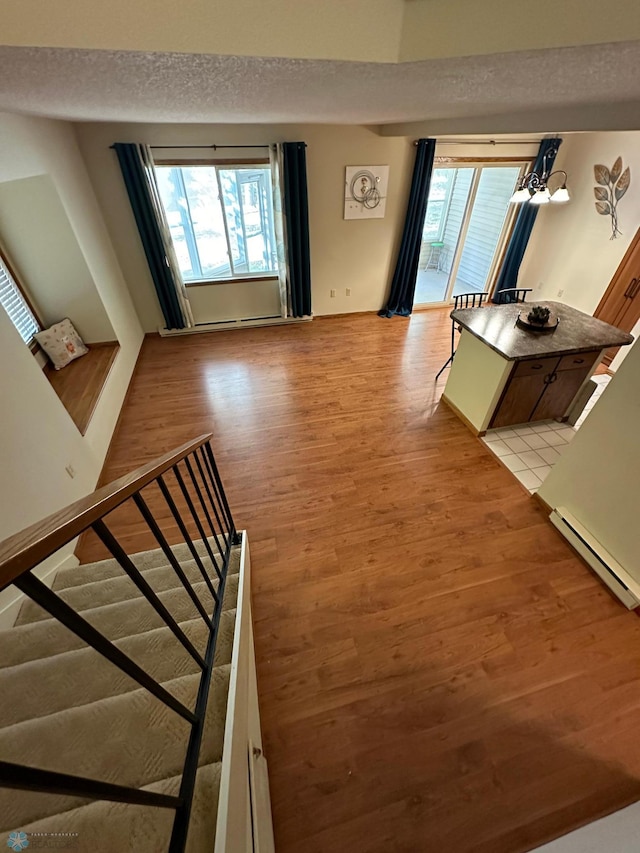 interior space featuring a wealth of natural light, a textured ceiling, baseboard heating, and light hardwood / wood-style flooring