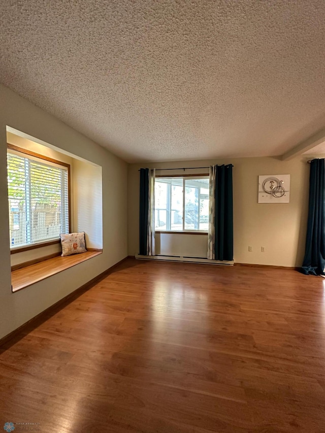 empty room featuring a healthy amount of sunlight, hardwood / wood-style flooring, and a textured ceiling