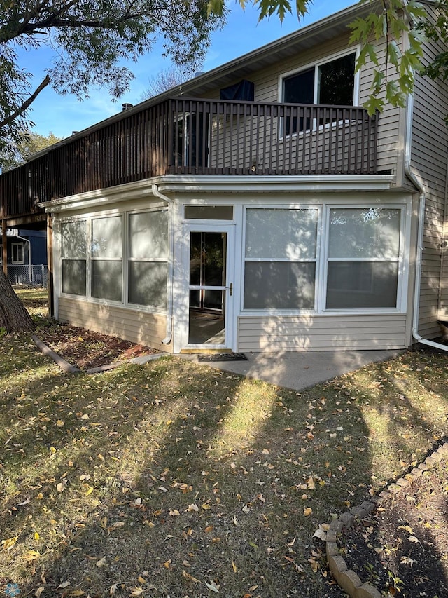 rear view of property featuring a lawn and a balcony