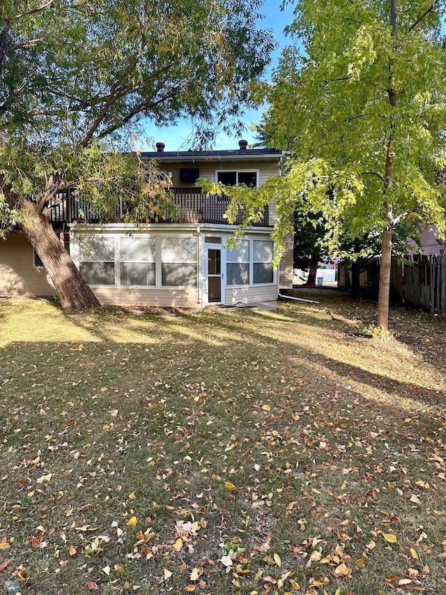 rear view of property with a yard and a balcony