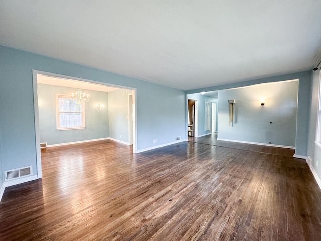 unfurnished living room featuring a notable chandelier and dark hardwood / wood-style flooring