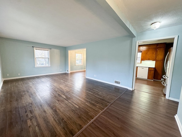 empty room with a textured ceiling and dark hardwood / wood-style floors