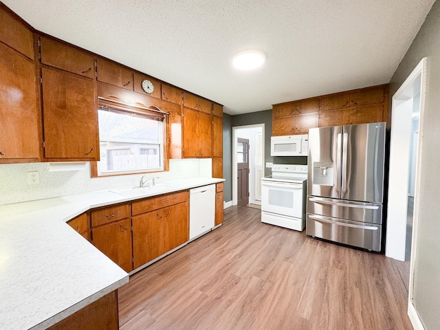 kitchen with sink, light hardwood / wood-style flooring, a textured ceiling, and white appliances