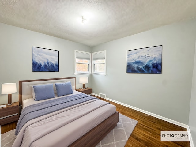 bedroom with wood-type flooring and a textured ceiling