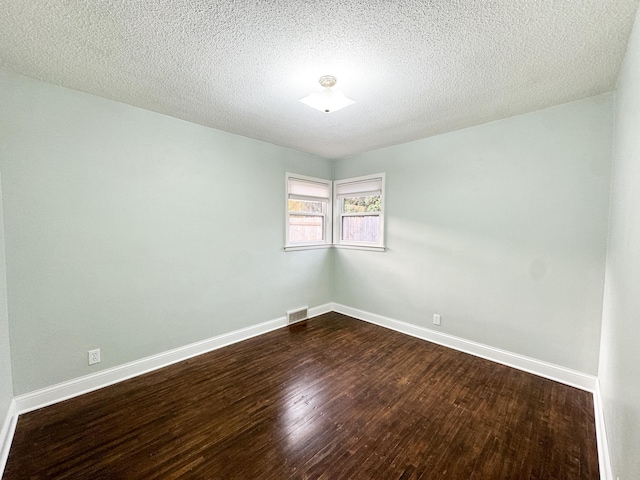 spare room featuring a textured ceiling and dark wood-type flooring