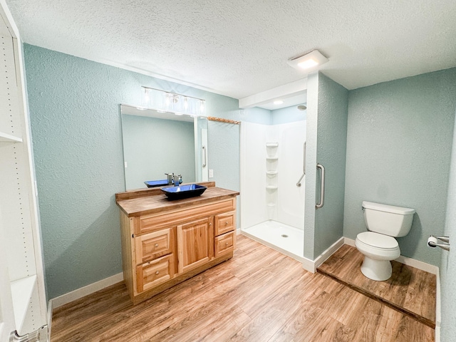 bathroom with hardwood / wood-style flooring, toilet, vanity, a textured ceiling, and an enclosed shower