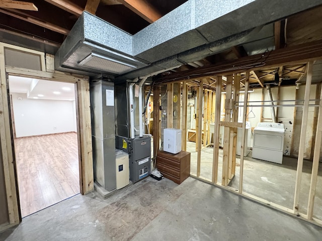 basement featuring washer / dryer, wood-type flooring, and heating unit