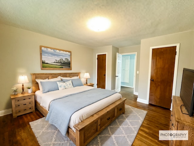 bedroom with a textured ceiling and dark hardwood / wood-style flooring