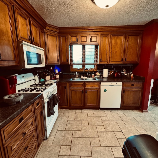 kitchen with dark stone counters, sink, a textured ceiling, white appliances, and tasteful backsplash