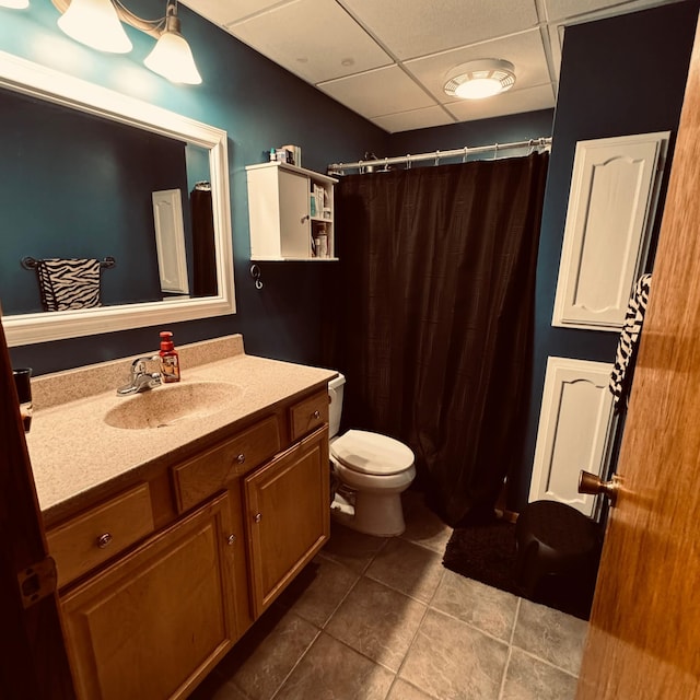 bathroom with vanity, a drop ceiling, toilet, and tile patterned floors