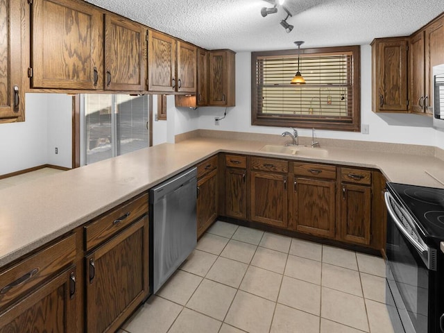 kitchen with sink, stainless steel appliances, decorative light fixtures, a textured ceiling, and light tile patterned floors